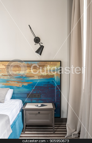 To use this stock image in your creative project, please select the size you need over to the right and click the "Add to Cart" button.
Your downloaded image will come with the Cutcaster watermark removed so don’t worry about the watermark you see on this page. Stylish hotel room stock photo, Beautiful hotel room with a light wall and a striped floor. There is a blue bed with a colorful wooden bedhead, nightstand with a tablet, black lamp on the wall, window with curtains. Vertical. by bezikus