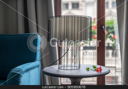 To use this stock image in your creative project, please select the size you need over to the right and click the "Add to Cart" button.
Your downloaded image will come with the Cutcaster watermark removed so don’t worry about the watermark you see on this page. Stylish hotel room stock photo, Metal lamp with a light lampshade on the round wooden table on the background of the glass door to the balcony in the hotel room. There is a blue sofa on the right side and a red flower near the lamp. by bezikus