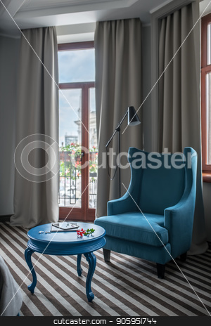 To use this stock image in your creative project, please select the size you need over to the right and click the "Add to Cart" button.
Your downloaded image will come with the Cutcaster watermark removed so don’t worry about the watermark you see on this page. Stylish hotel room stock photo, Bright hotel room with light walls and a striped floor. There is a round blue table with an armchair, window with curtains, glass door to the balcony, dark floor lamp. Vertical. by bezikus