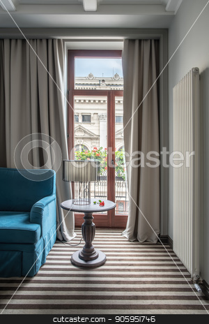 To use this stock image in your creative project, please select the size you need over to the right and click the "Add to Cart" button.
Your downloaded image will come with the Cutcaster watermark removed so don’t worry about the watermark you see on this page. Stylish hotel room stock photo, Modern hotel room with light walls and a striped floor. There is a blue sofa, small round table with a lamp with a lampshade, glass door to the balcony with curtains, white long radiator on the wall. by bezikus