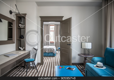 To use this stock image in your creative project, please select the size you need over to the right and click the "Add to Cart" button.
Your downloaded image will come with the Cutcaster watermark removed so don’t worry about the watermark you see on this page. Stylish hotel room stock photo, Light hotel room with a striped floor. There is a blue armchair with a hat, different tables, lamps, chair, shelves with decorations, mirror on the wall, door, bed, windows with curtains. Horizontal. by bezikus