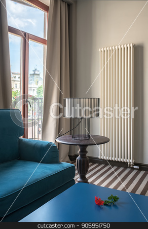 To use this stock image in your creative project, please select the size you need over to the right and click the "Add to Cart" button.
Your downloaded image will come with the Cutcaster watermark removed so don’t worry about the watermark you see on this page. Stylish hotel room stock photo, Elegant hotel room with light walls and a striped floor. There is a blue sofa with a same table, wooden round table with a lamp with a lampshade, glass door to the balcony with curtains, radiator. by bezikus