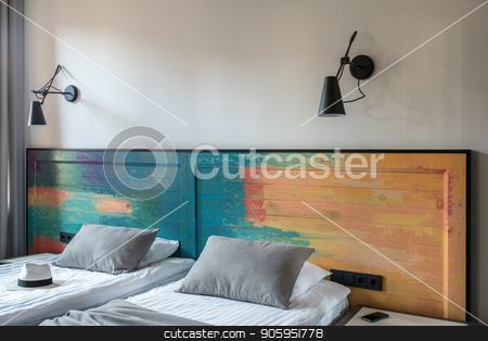 To use this stock image in your creative project, please select the size you need over to the right and click the "Add to Cart" button.
Your downloaded image will come with the Cutcaster watermark removed so don’t worry about the watermark you see on this page. Stylish hotel room stock photo, Nice room in a hotel with light walls. There are two beds with a colorful wooden bedhead, black lamps on the wall, curtain, nightstand with a smartphone. Horizontal. by bezikus