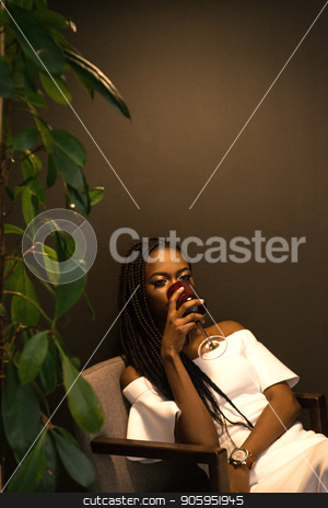 To use this stock image in your creative project, please select the size you need over to the right and click the "Add to Cart" button.
Your downloaded image will come with the Cutcaster watermark removed so don’t worry about the watermark you see on this page. African american woman drinking wine and sitting in an armchair near the plant. Dark background. stock photo, African american woman drinking wine and sitting in an armchair near the plant. Dark background. by Andrii Kobryn