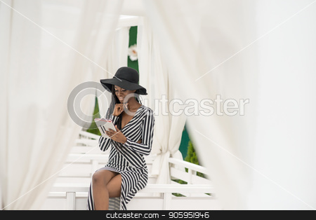 To use this stock image in your creative project, please select the size you need over to the right and click the "Add to Cart" button.
Your downloaded image will come with the Cutcaster watermark removed so don’t worry about the watermark you see on this page. Attractive afroamerican girl sitting on a white bench with the tablet in her hands in the yard of a restaurand. stock photo, Attractive afroamerican girl sitting by Andrii Kobryn