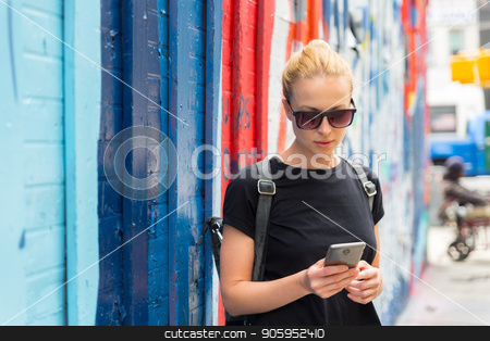 To use this stock image in your creative project, please select the size you need over to the right and click the "Add to Cart" button.
Your downloaded image will come with the Cutcaster watermark removed so don’t worry about the watermark you see on this page. Woman using smartphone against colorful graffiti wall in New York city, USA. stock photo, Closeup of female hipster with smart phone. Woman using smartphone against colorful graffiti wall in East Village, New York city, USA. by kasto