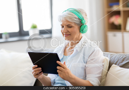 To use this stock image in your creative project, please select the size you need over to the right and click the "Add to Cart" button.
Your downloaded image will come with the Cutcaster watermark removed so don’t worry about the watermark you see on this page. senior woman in headphones listening to music stock photo, technology, people and lifestyle concept - happy senior woman in headphones and tablet pc computer listening to music at home by Syda Productions