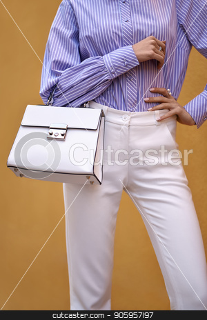 To use this stock image in your creative project, please select the size you need over to the right and click the "Add to Cart" button.
Your downloaded image will come with the Cutcaster watermark removed so don’t worry about the watermark you see on this page. Model with bag outdoors stock photo, Slim girl is posing with a white bag on the yellow wall background outdoors. She wears a white pants and a colorful striped shirt. Closeup vertical photo. by bezikus