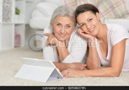 To use this stock image in your creative project, please select the size you need over to the right and click the "Add to Cart" button.
Your downloaded image will come with the Cutcaster watermark removed so don’t worry about the watermark you see on this page. Mother and her adult daughter lying on floor and looking at tabl stock photo, Mother and her adult daughter lying on floor and looking at tablet by Ruslan Huzau