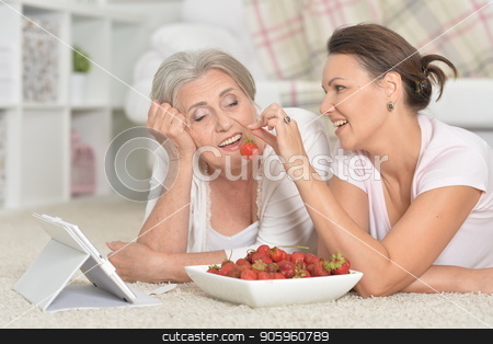 To use this stock image in your creative project, please select the size you need over to the right and click the "Add to Cart" button.
Your downloaded image will come with the Cutcaster watermark removed so don’t worry about the watermark you see on this page. Mother and her adult daughter lying on floor with tablet while e stock photo, Mother and her adult daughter lying on floor with tablet while eating fresh strawberries by Ruslan Huzau