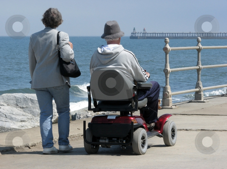 To use this stock image in your creative project, please select the size you need over to the right and click the "Add to Cart" button.
Your downloaded image will come with the Cutcaster watermark removed so don’t worry about the watermark you see on this page. Motorized wheelchair user stock photo, Elderly man riding motorized wheelchair with woman on seaside promenade. by Ronald Hudson