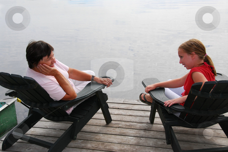 To use this stock image in your creative project, please select the size you need over to the right and click the "Add to Cart" button.
Your downloaded image will come with the Cutcaster watermark removed so don’t worry about the watermark you see on this page. Family on dock stock photo, Grandmother and granddaughter sitting in adirondack chairs on a dock having a conversation by Elena Elisseeva