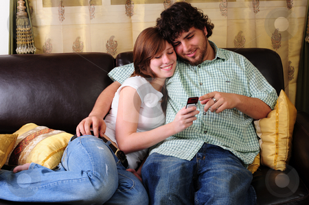 To use this stock image in your creative project, please select the size you need over to the right and click the "Add to Cart" button.
Your downloaded image will come with the Cutcaster watermark removed so don’t worry about the watermark you see on this page. Young couple relaxing on a couch. stock photo, Young couple relaxing on a brown leather couch while looking and pointing at a mobile phone. by Nicolaas Traut