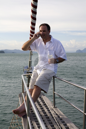 To use this stock image in your creative project, please select the size you need over to the right and click the "Add to Cart" button.
Your downloaded image will come with the Cutcaster watermark removed so don’t worry about the watermark you see on this page. Man on yacht with mobile phone and wine stock photo, Handsome man on deck of yacht with mobile phone and drinking wine by Magdalena Ascough