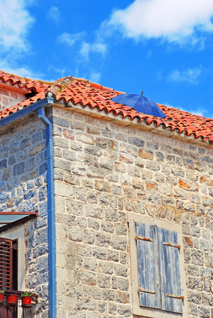 To use this stock image in your creative project, please select the size you need over to the right and click the "Add to Cart" button.
Your downloaded image will come with the Cutcaster watermark removed so don’t worry about the watermark you see on this page. Umbrella on roof. Rain protection stock photo, Old stone house exterior in Montenegro - Budva, umbrella on roof by Julija Sapic