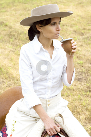 To use this stock image in your creative project, please select the size you need over to the right and click the "Add to Cart" button.
Your downloaded image will come with the Cutcaster watermark removed so don’t worry about the watermark you see on this page. Argentinean Gaucha on her Horse stock photo, A young Argentinean gaucha relaxing with yerba mate while riding her horse. by Lee Torrens