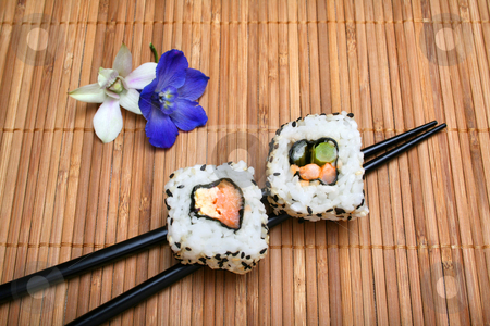 To use this stock image in your creative project, please select the size you need over to the right and click the "Add to Cart" button.
Your downloaded image will come with the Cutcaster watermark removed so don’t worry about the watermark you see on this page. Sushi stock photo, Two pieces of sushi resting on chopsticks on bamboo mat with flower garnish. by Clay Anthony