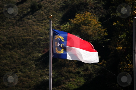To use this stock image in your creative project, please select the size you need over to the right and click the "Add to Cart" button.
Your downloaded image will come with the Cutcaster watermark removed so don’t worry about the watermark you see on this page. Flag in the wind stock photo, North Carolina flag blowing in the breeze by Tim Markley