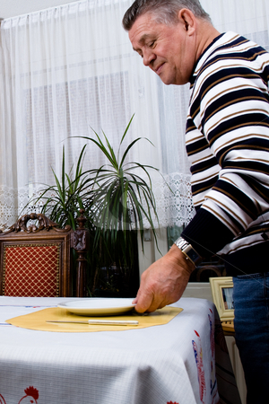 To use this stock image in your creative project, please select the size you need over to the right and click the "Add to Cart" button.
Your downloaded image will come with the Cutcaster watermark removed so don’t worry about the watermark you see on this page. Gradfather is setting the table for breakfast stock photo, Senior man is preparing the breakfast table by Frenk and Danielle Kaufmann