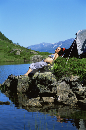 To use this stock image in your creative project, please select the size you need over to the right and click the "Add to Cart" button.
Your downloaded image will come with the Cutcaster watermark removed so don’t worry about the watermark you see on this page. Young woman sunbathing on rocks next to lake stock photo, by Monkey Business Images