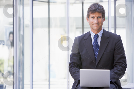 To use this stock image in your creative project, please select the size you need over to the right and click the "Add to Cart" button.
Your downloaded image will come with the Cutcaster watermark removed so don’t worry about the watermark you see on this page. Businessman sitting in office lobby using laptop smiling stock photo, by Monkey Business Images