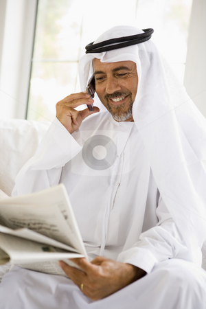 To use this stock image in your creative project, please select the size you need over to the right and click the "Add to Cart" button.
Your downloaded image will come with the Cutcaster watermark removed so don’t worry about the watermark you see on this page. A Middle Eastern man talking on a mobile phone while reading a n stock photo, by Monkey Business Images