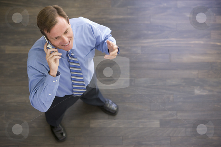 To use this stock image in your creative project, please select the size you need over to the right and click the "Add to Cart" button.
Your downloaded image will come with the Cutcaster watermark removed so don’t worry about the watermark you see on this page. Businessman standing indoors using cellular phone and smiling stock photo, by Monkey Business Images