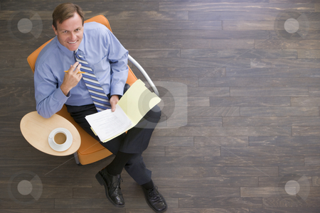 To use this stock image in your creative project, please select the size you need over to the right and click the "Add to Cart" button.
Your downloaded image will come with the Cutcaster watermark removed so don’t worry about the watermark you see on this page. Businessman sitting indoors with coffee and folder smiling stock photo, by Monkey Business Images