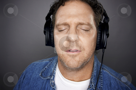 To use this stock image in your creative project, please select the size you need over to the right and click the "Add to Cart" button.
Your downloaded image will come with the Cutcaster watermark removed so don’t worry about the watermark you see on this page. Man With Headphones stock photo, Man with Eyes Shut Wearing Headphones Enjoying His Music on a Grey Background. by Andy Dean