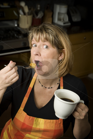 To use this stock image in your creative project, please select the size you need over to the right and click the "Add to Cart" button.
Your downloaded image will come with the Cutcaster watermark removed so don’t worry about the watermark you see on this page. Woman eating in kitchen stock photo, Woman in kitchen with coffee eating from a fork by Scott Griessel