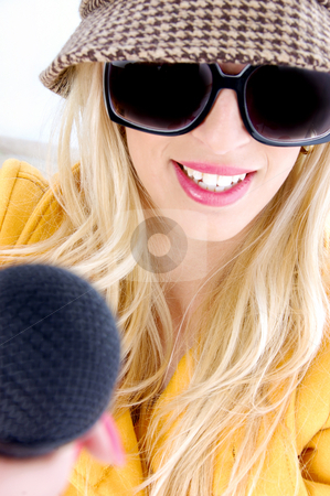 To use this stock image in your creative project, please select the size you need over to the right and click the "Add to Cart" button.
Your downloaded image will come with the Cutcaster watermark removed so don’t worry about the watermark you see on this page. Smiling woman in sunglasses holding mic stock photo, Front view of smiling woman in sunglasses holding mic by Imagery Majestic