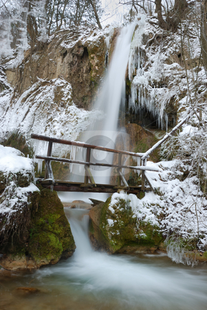 To use this stock image in your creative project, please select the size you need over to the right and click the "Add to Cart" button.
Your downloaded image will come with the Cutcaster watermark removed so don’t worry about the watermark you see on this page. Winter Waterfall stock photo, Waterfall with icicles and snow around with a small wooden bridge on a winter day. by Denis Radovanovic
