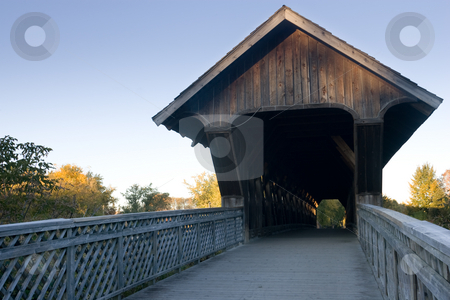 To use this stock image in your creative project, please select the size you need over to the right and click the "Add to Cart" button.
Your downloaded image will come with the Cutcaster watermark removed so don’t worry about the watermark you see on this page. Covered walking bridge - front view stock photo, A view of the covered walking bridge, located in Guelph, Ontario, Canada, withe a blue sky background, and surrounding fall colours. by Kevin Woodrow