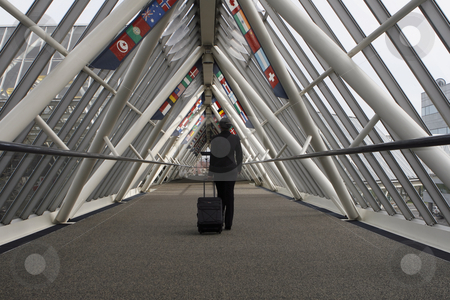 To use this stock image in your creative project, please select the size you need over to the right and click the "Add to Cart" button.
Your downloaded image will come with the Cutcaster watermark removed so don’t worry about the watermark you see on this page. Businesswoman in Walkway stock photo, Businesswoman walking through a walkway / skybridge pulling her luggage behind her. The walkway is lined with flags. Horizontally framed shot with the woman walking away from the camera. by Orange Line Media