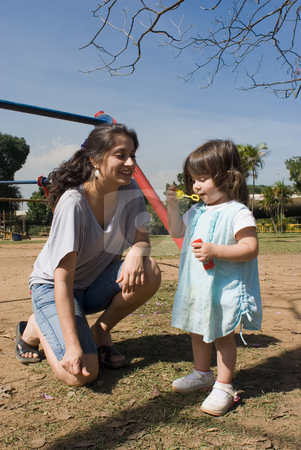 To use this stock image in your creative project, please select the size you need over to the right and click the "Add to Cart" button.
Your downloaded image will come with the Cutcaster watermark removed so don’t worry about the watermark you see on this page. Blowing Bubbles with Mom stock photo, Outdoor shot of a little girl by a swing-set blowing bubbles, while her smiling mom kneels next to her. by Orange Line Media