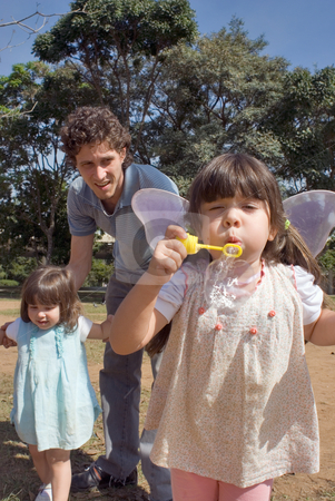To use this stock image in your creative project, please select the size you need over to the right and click the "Add to Cart" button.
Your downloaded image will come with the Cutcaster watermark removed so don’t worry about the watermark you see on this page. Young Girl Blowing Bubbles stock photo, Cute young girl blowing bubbles while her younger sister and father look on. Vertically framed shot. by Orange Line Media