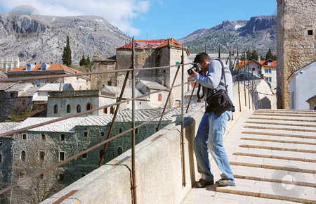 To use this stock image in your creative project, please select the size you need over to the right and click the "Add to Cart" button.
Your downloaded image will come with the Cutcaster watermark removed so don’t worry about the watermark you see on this page. Photographer shooting stock photo, A photographer shooting from the Old Bridge in Mostar by Ivan Paunovic