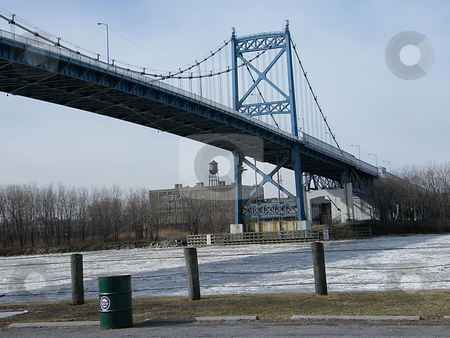 To use this stock image in your creative project, please select the size you need over to the right and click the "Add to Cart" button.
Your downloaded image will come with the Cutcaster watermark removed so don’t worry about the watermark you see on this page. Anthony Wayne Suspension Bridge stock photo, Anthony Wayne Suspension Bridge also known as The High Level Bridge crossing Maumee River in Winter. The bridge was built in 1931. The RIver's surface is frozen. Photo taken at International Park in Toledo Ohio. The bridge connects the East Side of Toledo to other (main) side of the city. Old Great Lakes Terminal Warehouse in the background on the West Shore of the River, Garbage can on East Shore has the Toledo Pride Logo/Symbol on it. by Dazz Lee Photography