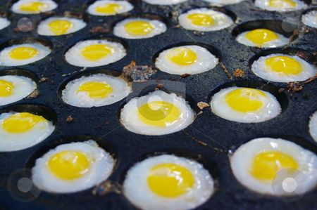 To use this stock image in your creative project, please select the size you need over to the right and click the "Add to Cart" button.
Your downloaded image will come with the Cutcaster watermark removed so don’t worry about the watermark you see on this page. Fried eggs stock photo, Eggs being fried in a cast iron aebleskiver pan by Martin Darley