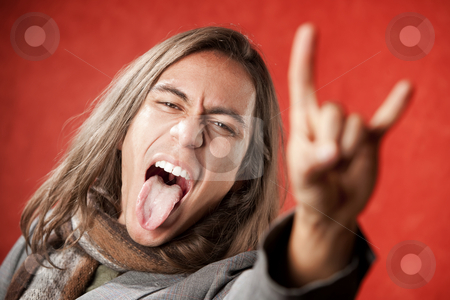 To use this stock image in your creative project, please select the size you need over to the right and click the "Add to Cart" button.
Your downloaded image will come with the Cutcaster watermark removed so don’t worry about the watermark you see on this page. Handsome Young Man Making a Hand Gesture stock photo, Closeup Portrait of Handsome Young Man with Long Hair Making Hand gesture and Sticking Out Tongue by Scott Griessel