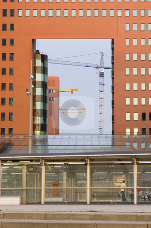 To use this stock image in your creative project, please select the size you need over to the right and click the "Add to Cart" button.
Your downloaded image will come with the Cutcaster watermark removed so don’t worry about the watermark you see on this page. Inner City see-through stock photo, A glimpse underneath a modern office building at a construction site, with cranes lit by the last rays of the sun on a summer evening by Corepics VOF