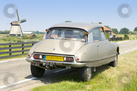 To use this stock image in your creative project, please select the size you need over to the right and click the "Add to Cart" button.
Your downloaded image will come with the Cutcaster watermark removed so don’t worry about the watermark you see on this page. Dutch scene with a French Classic Car stock photo, A vintage 1973 Citroen DS parked on a country road with a windmill in the distance on a bright summer day. by Corepics VOF