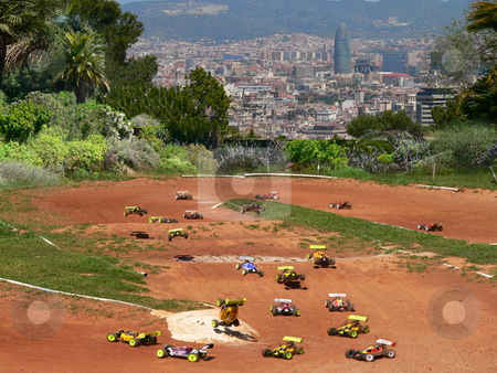 To use this stock image in your creative project, please select the size you need over to the right and click the "Add to Cart" button.
Your downloaded image will come with the Cutcaster watermark removed so don’t worry about the watermark you see on this page. Minature motor racing stock photo, Model cars racing around a dirt track with a view of palm trees and the agbar tower of barcelona in spain by Casinozack