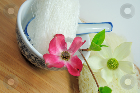 To use this stock image in your creative project, please select the size you need over to the right and click the "Add to Cart" button.
Your downloaded image will come with the Cutcaster watermark removed so don’t worry about the watermark you see on this page. Rice And Mung Bean Noodles stock photo, Dried asin noodles in a blue and white ceramic oriental bowl with spoon on a bamboo cutting board topped with pink and white Dogwood flowers by Lynn Bendickson