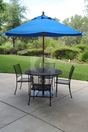 To use this stock image in your creative project, please select the size you need over to the right and click the "Add to Cart" button.
Your downloaded image will come with the Cutcaster watermark removed so don’t worry about the watermark you see on this page. Wrought Iron Table With Umbrella stock photo, Blue umbrella, table and chairs on a patio in a graden setting by Lynn Bendickson