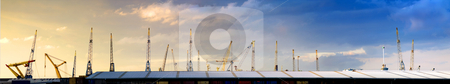 To use this stock image in your creative project, please select the size you need over to the right and click the "Add to Cart" button.
Your downloaded image will come with the Cutcaster watermark removed so don’t worry about the watermark you see on this page. Cranes skyline stock photo, Panoramic image filled with a warehouse roof with cranes, sticking out like pins in a cushon with a natural gradient from yellow to blue in the sky due to the setting sun by Corepics VOF