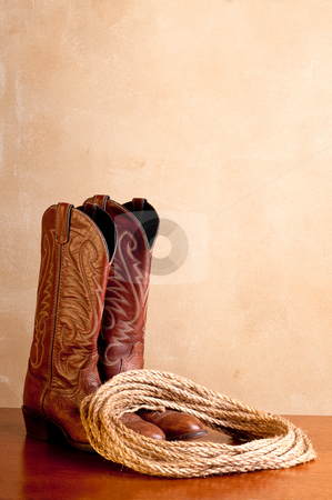 To use this stock image in your creative project, please select the size you need over to the right and click the "Add to Cart" button.
Your downloaded image will come with the Cutcaster watermark removed so don’t worry about the watermark you see on this page. A vertical image of a pair of brown cowboy boots and a coil of r stock photo, A vertical image of a pair of brown cowboy boots and a coil of rope on a wooded surface with an old textured background by Vince Clements
