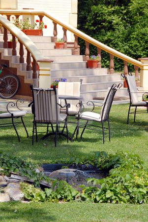 To use this stock image in your creative project, please select the size you need over to the right and click the "Add to Cart" button.
Your downloaded image will come with the Cutcaster watermark removed so don’t worry about the watermark you see on this page. Home yard stock photo, House stairs with flowerpots and tables on lawn in yard by Julija Sapic