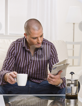 To use this stock image in your creative project, please select the size you need over to the right and click the "Add to Cart" button.
Your downloaded image will come with the Cutcaster watermark removed so don’t worry about the watermark you see on this page. Man Reading Paper - Vertical stock photo, A young, attractive man is sitting at a coffee table, drinking coffee and reading a newspaper. He is looking away from the camera. Vertically framed shot. by Jonathan Ross