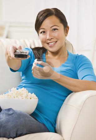To use this stock image in your creative project, please select the size you need over to the right and click the "Add to Cart" button.
Your downloaded image will come with the Cutcaster watermark removed so don’t worry about the watermark you see on this page. Beautiful Asian Woman Watching T.V. stock photo, A beautiful young asian woman sitting on a couch. She is holding a bowl of popcorn and is using a remote. She is smiling directly at the camera. Vertically framed shot. by Jonathan Ross